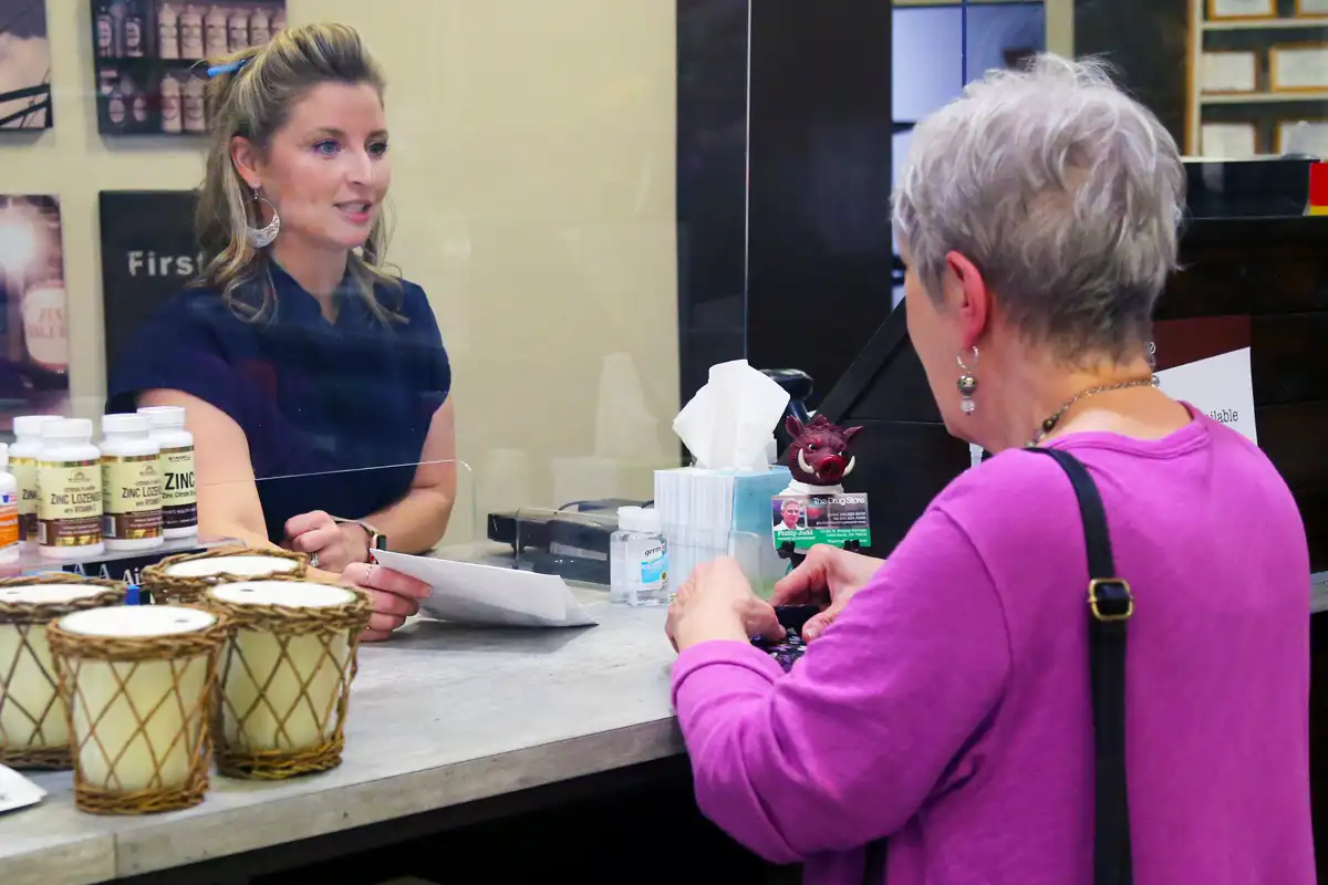 Holly handing prescription to customer at checkout