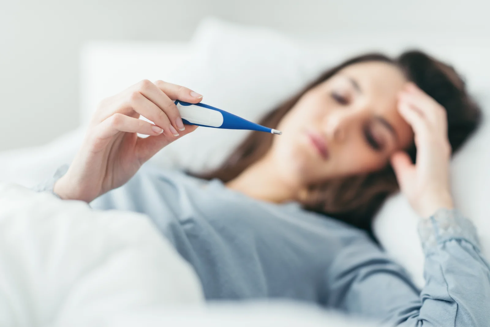 woman in bed reading thermometer
