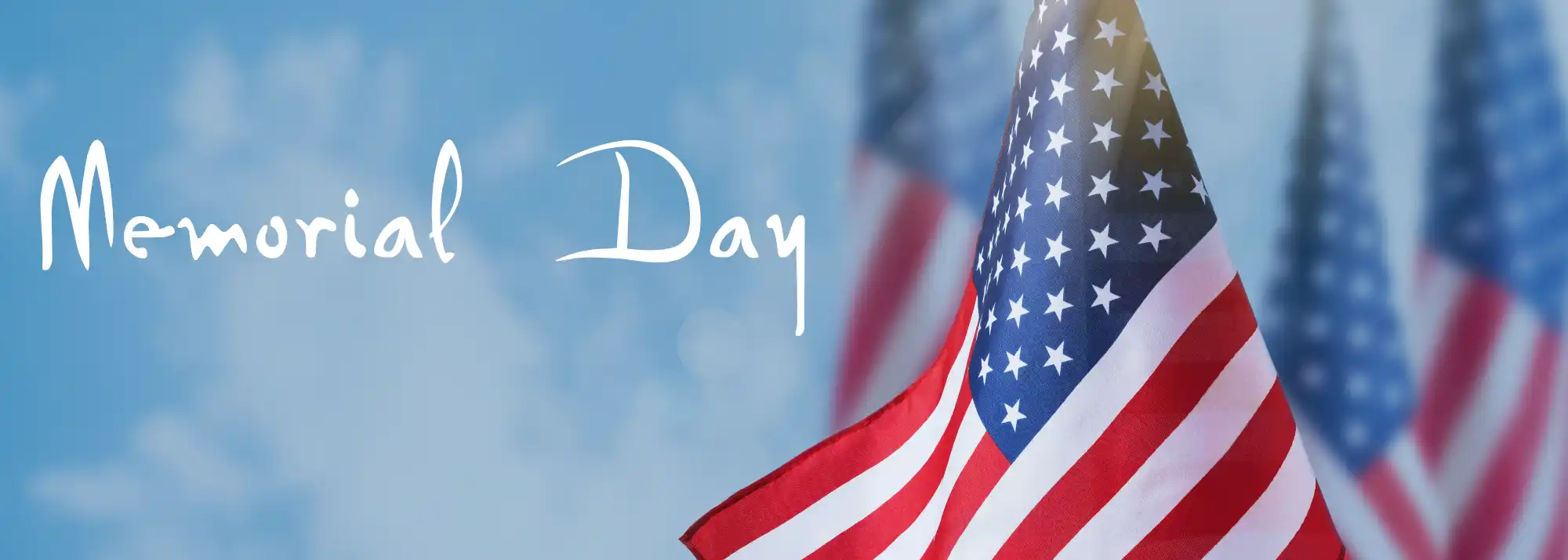 Memorial Day text with US flags against blue sky